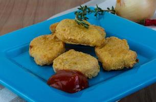 Nuggets on the plate and wooden background photo