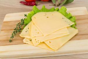 Sliced cheddar on wooden board and wooden background photo