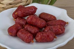 mini salami en el plato y fondo de madera foto