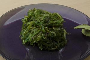 Chuka salad on the plate and wooden background photo