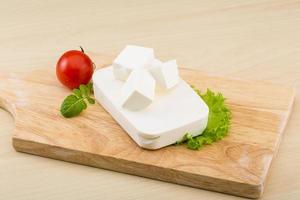 Feta cheese on wooden board and wooden background photo