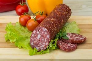 Salami on wooden board and wooden background photo