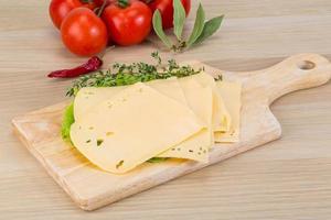 Sliced cheddar on wooden board and wooden background photo