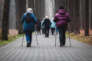 caminar en poste para personas mayores, un grupo de mujeres camina por la buena salud en el parque foto