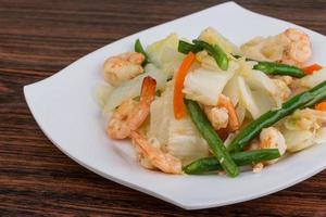 Shrimp salad on the plate and wooden background photo