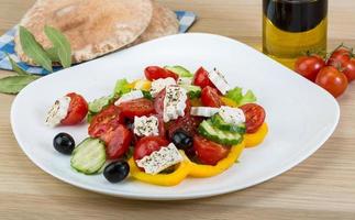 Greek salad on the plate and wooden background photo
