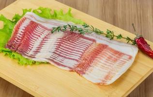 Bacon on wooden board and wooden background photo