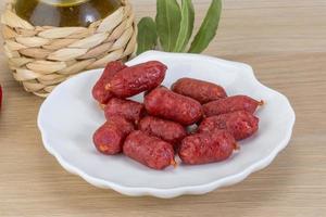 Mini salami on the plate and wooden background photo