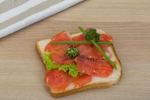 Salmon sandwich on wooden background photo