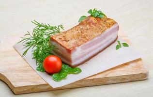 Raw bacon on wooden board and wooden background photo