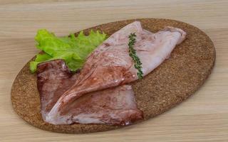 Raw squids on wooden board and wooden background photo