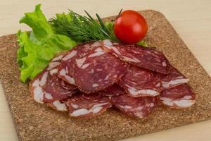 Sliced salami on wooden board and wooden background photo