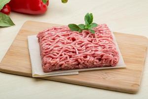 Minced meat on wooden board and wooden background photo