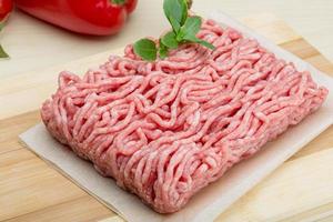 Minced meat on wooden board and wooden background photo