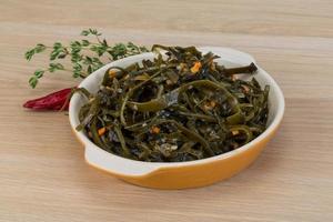 Laminaria salad in a bowl on wooden background photo