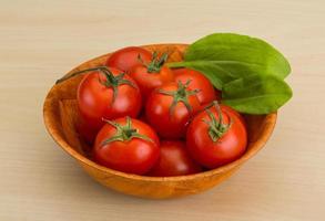Cherry tomatoes in a bowl on wooden background photo