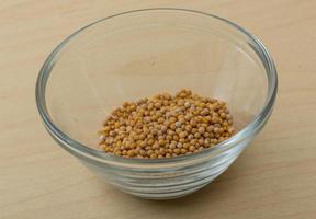 Mustard seeds in a bowl on wooden background photo