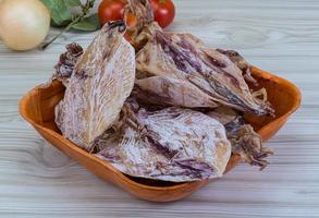 Dried squid in a bowl on wooden background photo