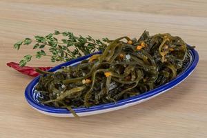 Laminaria salad in a bowl on wooden background photo