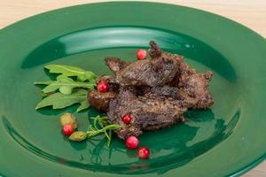 Roasted venison on the plate and wooden background photo