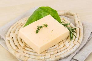 Yellow cheese on wooden board and wooden background photo