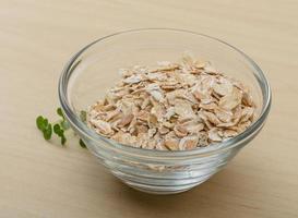 Dry oats in a bowl on wooden background photo