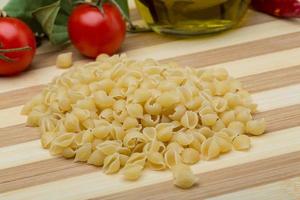 pasta de concha sobre tablero de madera y fondo de madera foto