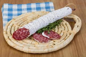 Fuet sausage on wooden board and wooden background photo