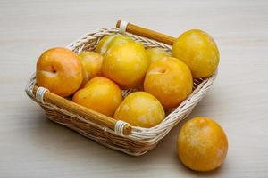 Yellow plums in a basket on wooden background photo