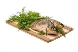 Raw Crucian on wooden board and white background photo