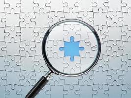 Search for missing puzzle pieces with a magnifying glass. Concept image of detecting a defect. photo