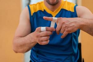 un jugador de baloncesto discapacitado se pone un corsé y se venda los brazos y los dedos para prepararse para un partido en la arena foto