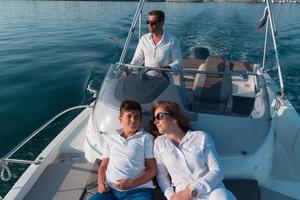 A senior couple in casual outfits with their son enjoy while riding a boat at sea at sunset. The concept of a happy family. Selective focus photo