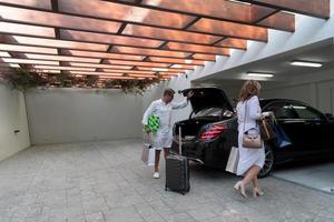 A photo of a modern family carrying suitcases from a garage to their luxury seaside home during a vacation. Vacation concept. Selective focus