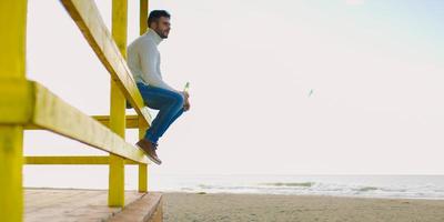 hombre bebiendo cerveza en la playa foto