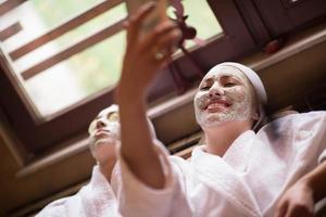 women is getting facial clay mask at spa photo