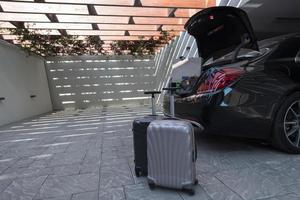 A photo of a suitcase standing next to a car in a luxury garage. Selective focus