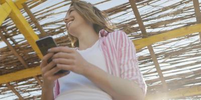 mujer smartphone enviando mensajes de texto por teléfono celular en la playa foto