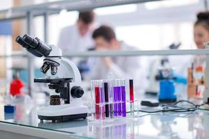 Microscope on the workplace near test tubes photo