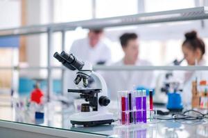 Microscope on the workplace near test tubes photo