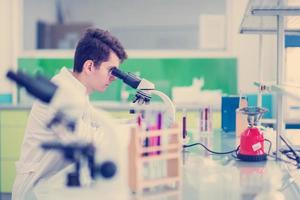 estudiante científico mirando a través de un microscopio foto