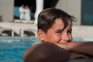 el niño disfruta de un día de verano nadando en la piscina. el concepto de unas vacaciones familiares. enfoque selectivo foto