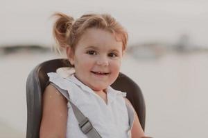 A portrait of a smiling little girl sitting in a bicycle seat. Selective focus photo