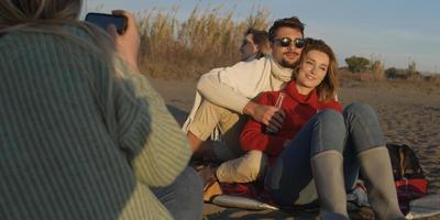 Loving Young Couple Sitting On The Beach beside Campfire drinking beer photo