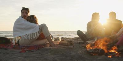 Loving Young Couple Sitting On The Beach beside Campfire drinking beer photo