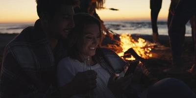 Couple enjoying bonfire with friends on beach photo