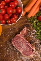 Juicy slice of raw steak on wooden table photo