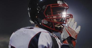 American Football Player Putting On Helmet on large stadium with lights in background photo