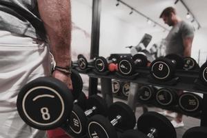 Struggling with age. Confident senior man exercising with dumbbells in health club. Selective focus photo