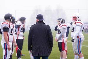 jugadores de fútbol americano discutiendo estrategia con el entrenador foto